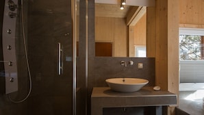 A modern bathroom with a glass-enclosed shower, a freestanding bathtub, and a large sink with a wooden countertop. - Cabin in Turrach With Sauna and Wi-fi (Stadl-Predlitz)
