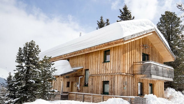 A wooden chalet with a snow-covered roof, surrounded by snow and trees. - Cabin in Turrach With Sauna and Wi-fi (Stadl-Predlitz)