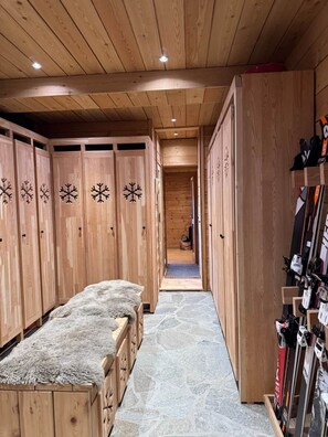 A wooden hallway with lockers, a fur-covered bench, and ski equipment. - L'Evidence · Chalet luxe 10 pers · Sauna (Saint-Étienne-de-Tinée)