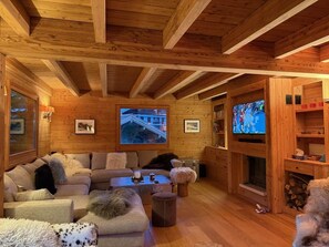 Ein gemütlicher Holzraum mit einem Ecksofa, einem Kamin und einem Fernseher.