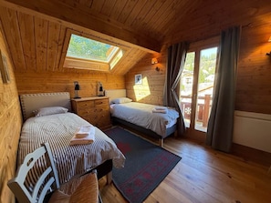 A cozy cabin bedroom with two beds, a skylight, and a view of the outdoors. - L'Evidence · Chalet luxe 10 pers · Sauna (Saint-Étienne-de-Tinée)