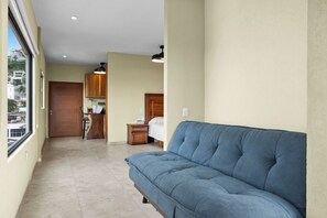A hallway with a blue sofa, wooden cabinets, and a door leading to a room. - The Malecon Penthouse Studio 1 Block to Beach & Sea (Puerto Vallarta)