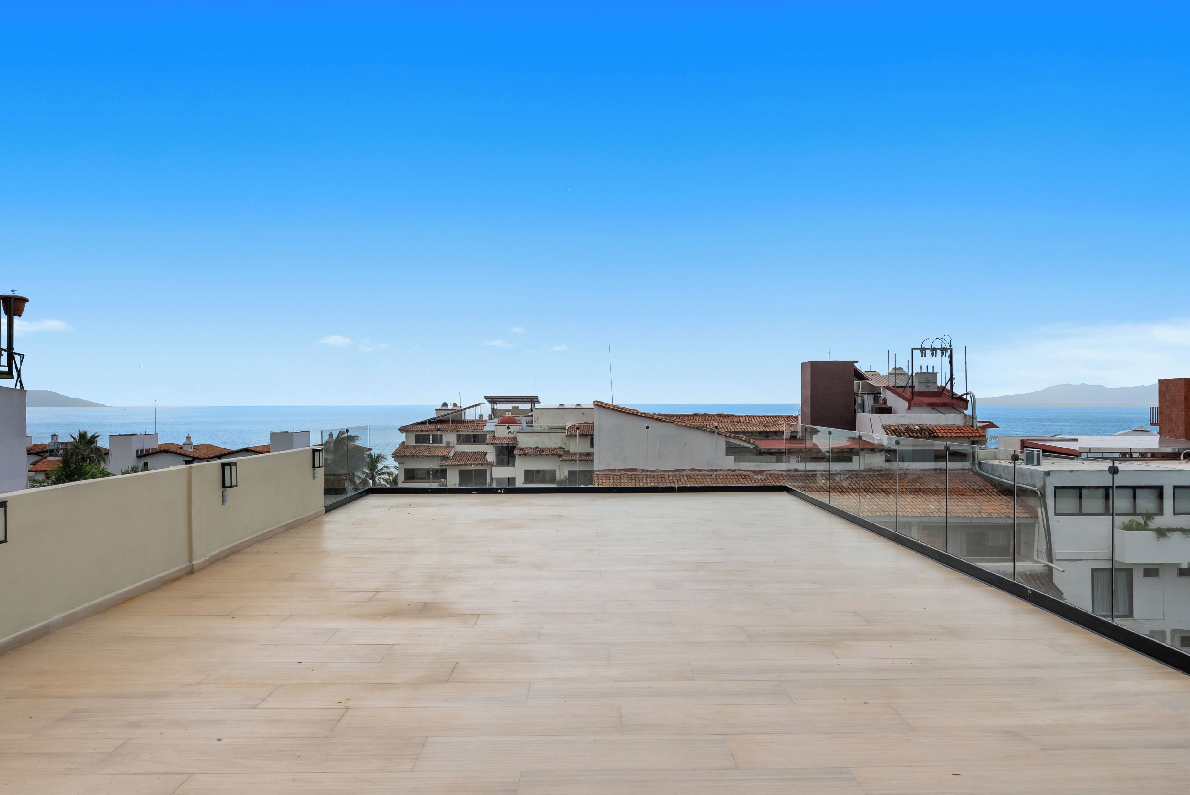 Una terraza en la azotea con vistas al mar y edificios cercanos.