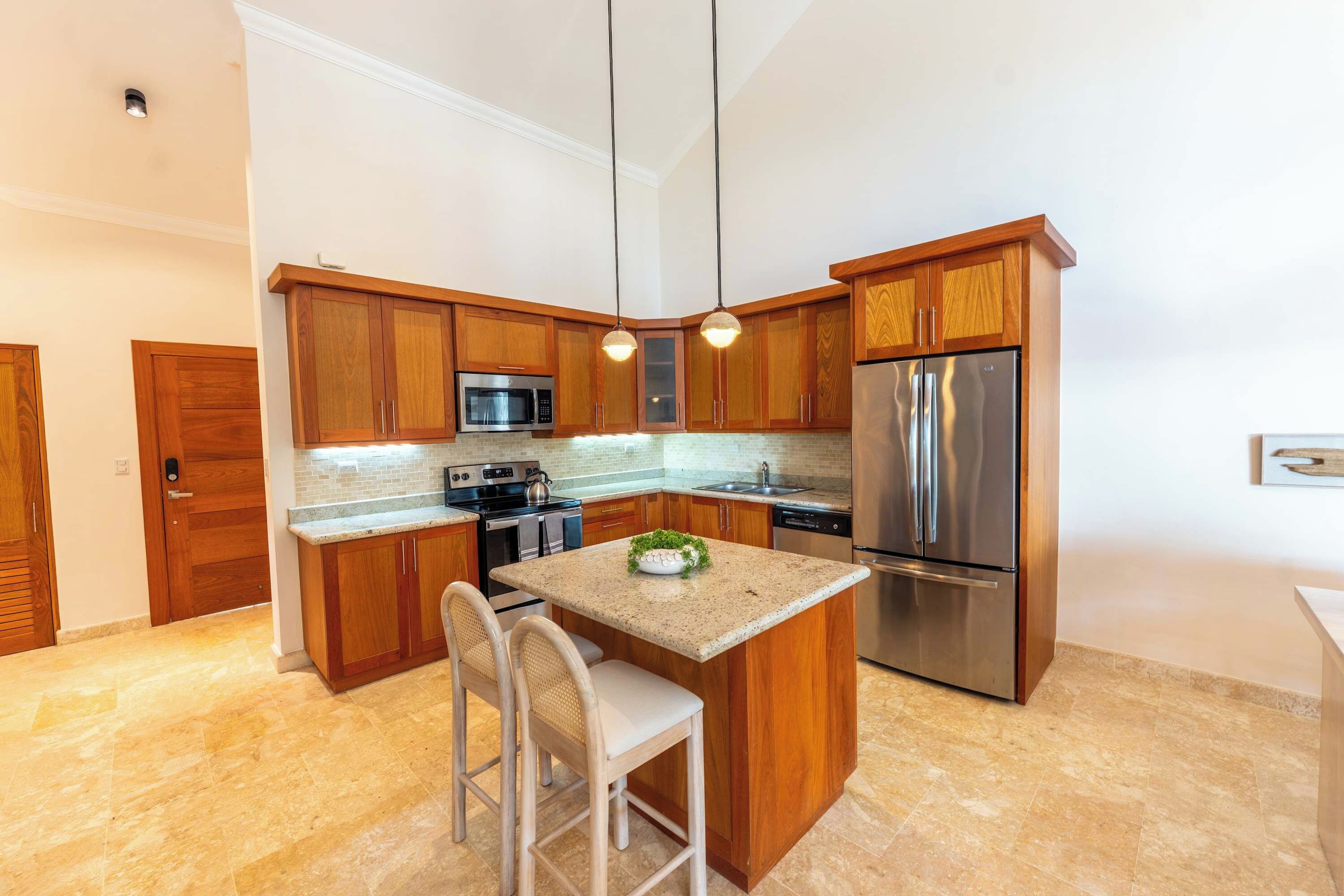 Een moderne keuken met houten kastjes, roestvrijstalen apparatuur en een centraal eiland met zitplaatsen.