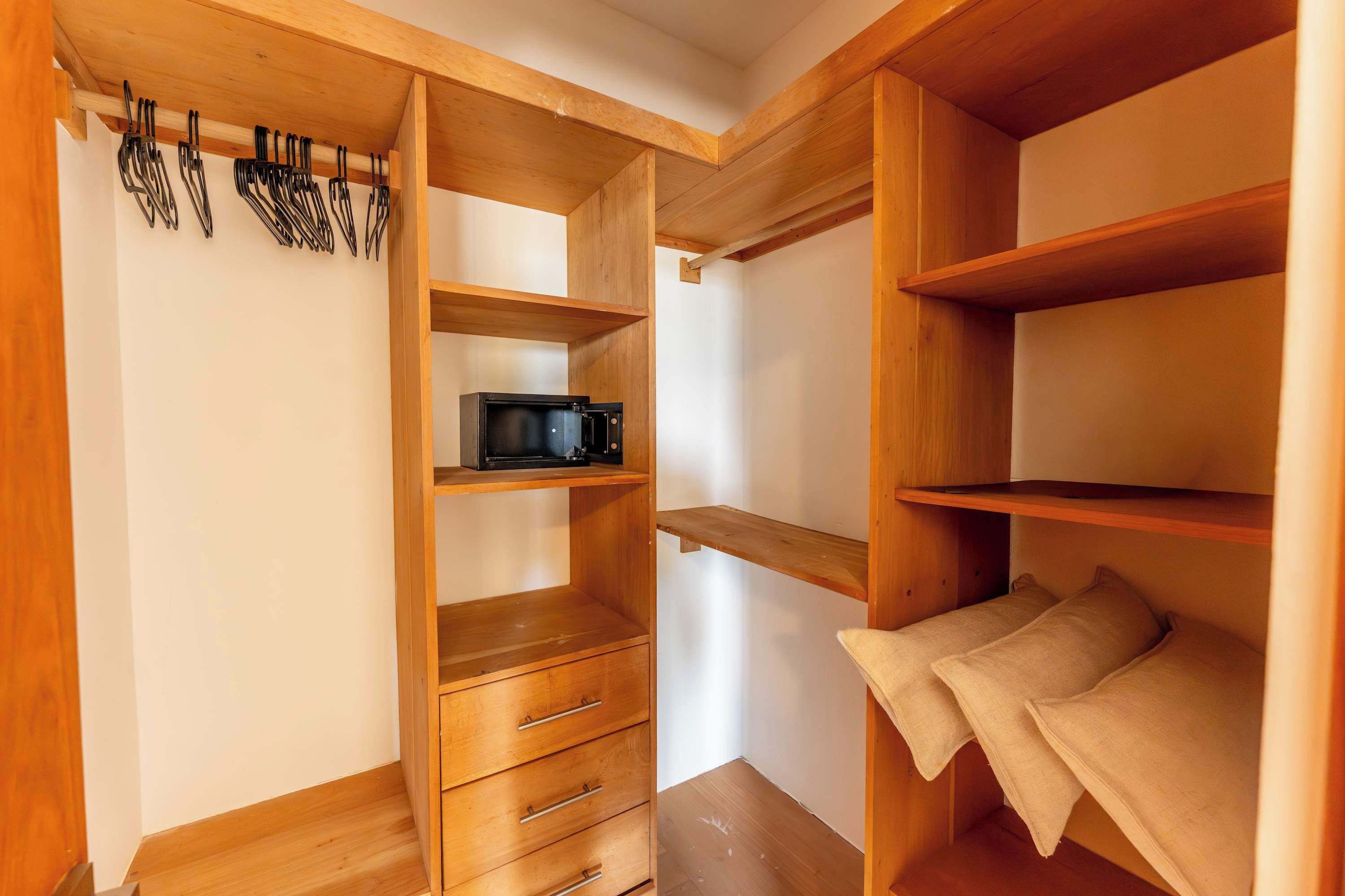 Un mueble compacto con estantes de madera, un microondas y un tendedero para utensilios.