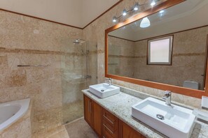 A modern bathroom with a glass-enclosed shower, two sinks, and a large mirror. - Luxury Beachfront Apartment in Sosua! (Sosúa)