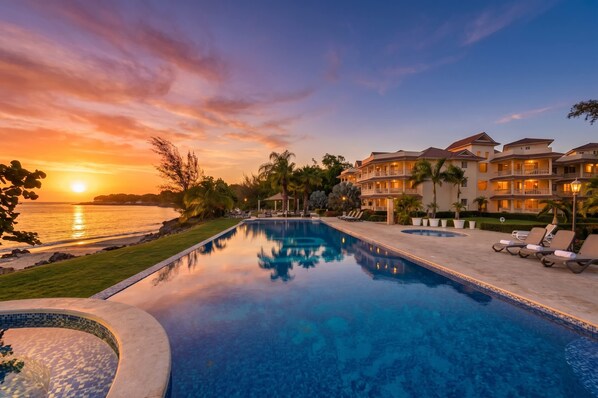 A resort with a swimming pool, beachfront view, and multiple-story buildings. - Luxury Beachfront Apartment in Sosua! (Sosúa)