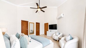 Quarto moderno com cama, sofá, TV e ventilador de teto.