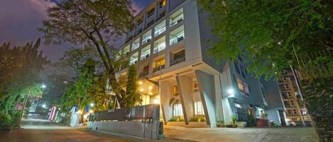 A multi-story hotel with a modern architectural design, featuring a central courtyard and a well-lit entrance.