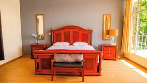 A bedroom with a large bed, two nightstands, a bench, and a window with curtains. - Quinta Sunset Coatepeque Lake  (Santa Ana)