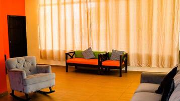 A living room with a sofa, armchair, and a small table with decorative pillows.