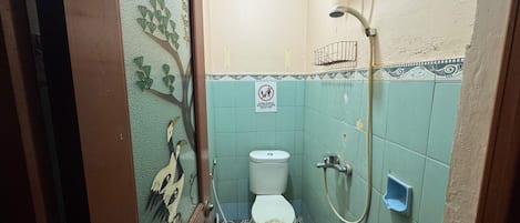 A small bathroom with a toilet, a shower, and a sink.