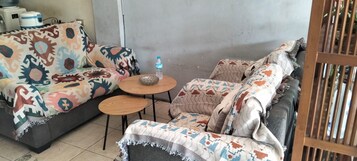 A room with a sofa set, a small round table, and a water bottle.