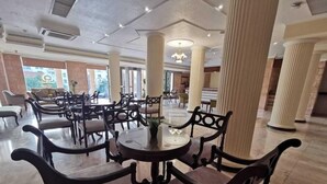 A spacious hotel lobby with high ceilings, large columns, and a central round table with chairs. - Petra Edom Hotel (Wadi Musa)