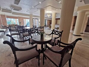 A spacious hotel lobby with high ceilings, large columns, and a central round table with chairs. - Petra Edom Hotel (Wadi Musa)