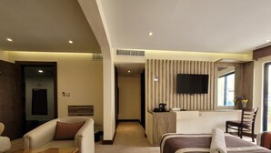 A hotel room with a bed, a sofa, a desk, a television, and a window with a view. - Petra Edom Hotel (Wadi Musa)