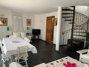 Ein Hotelzimmer mit Esstisch, Stühlen, Fernseher, einer Treppe und Bildern an den Wänden.