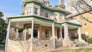 A two-story building with a stone facade, a wrap-around porch, and a symmetrical design.