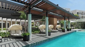 Zona de piscina con sillones de descanso y un área de estar cubierta.
