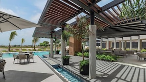 Un área junto a la piscina con zona de estar cubierta, sillas de descanso y una piscina pequeña.