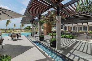 Un espace aménagé au bord de la piscine, comprenant un coin salon couvert, des chaises longues et une petite piscine.