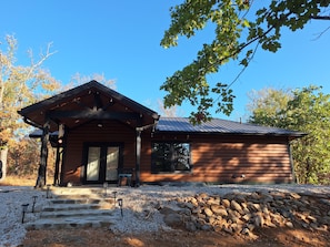 A wooden cabin with a porch, steps leading to the entrance, and a gravel driveway. - Secluded Sunset a charming rustic 1-bedroom cabin in Ringold (Ringold)