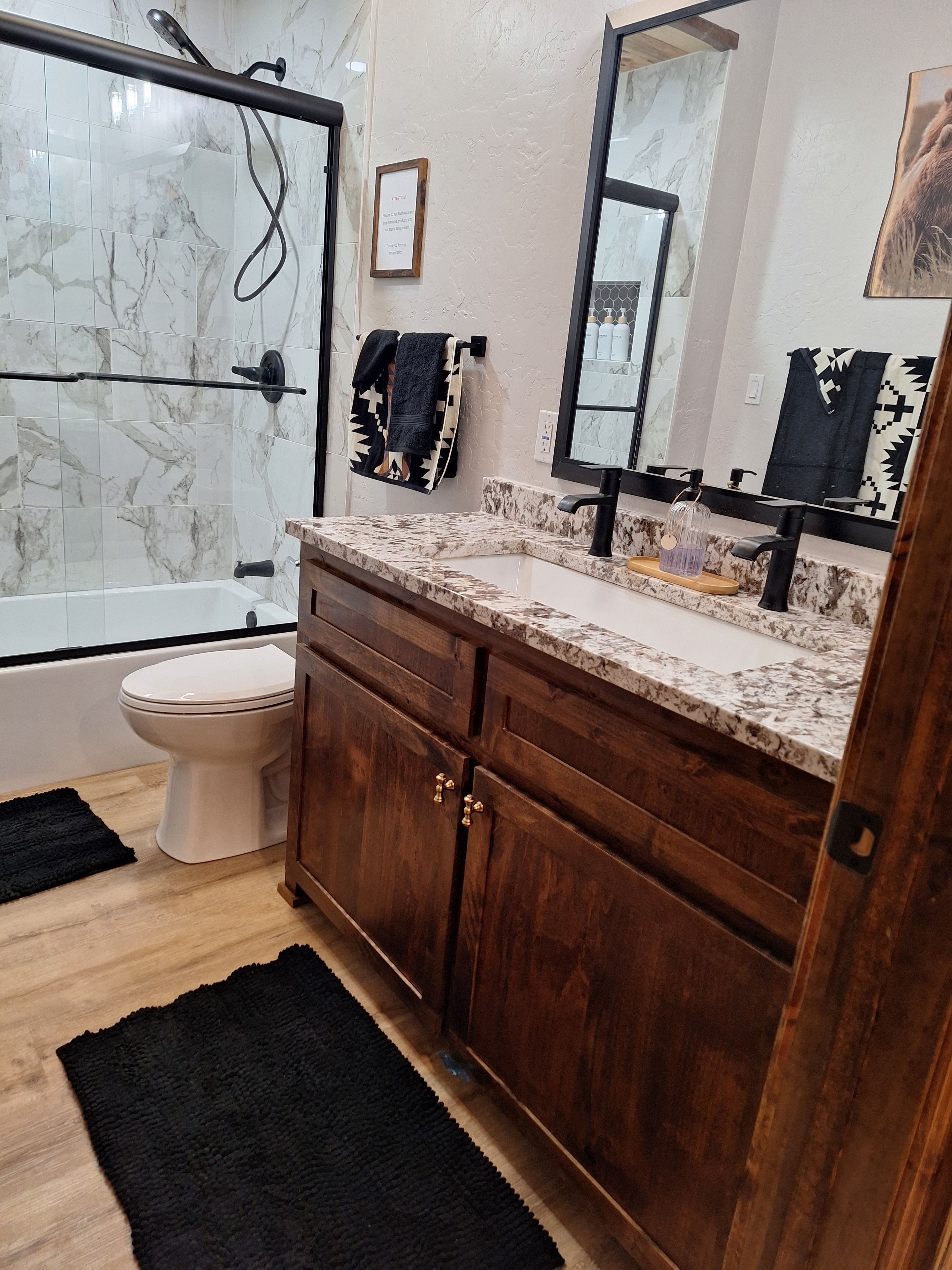Ein Badezimmer mit Dusche, Toilette und Waschtisch mit Spiegel.