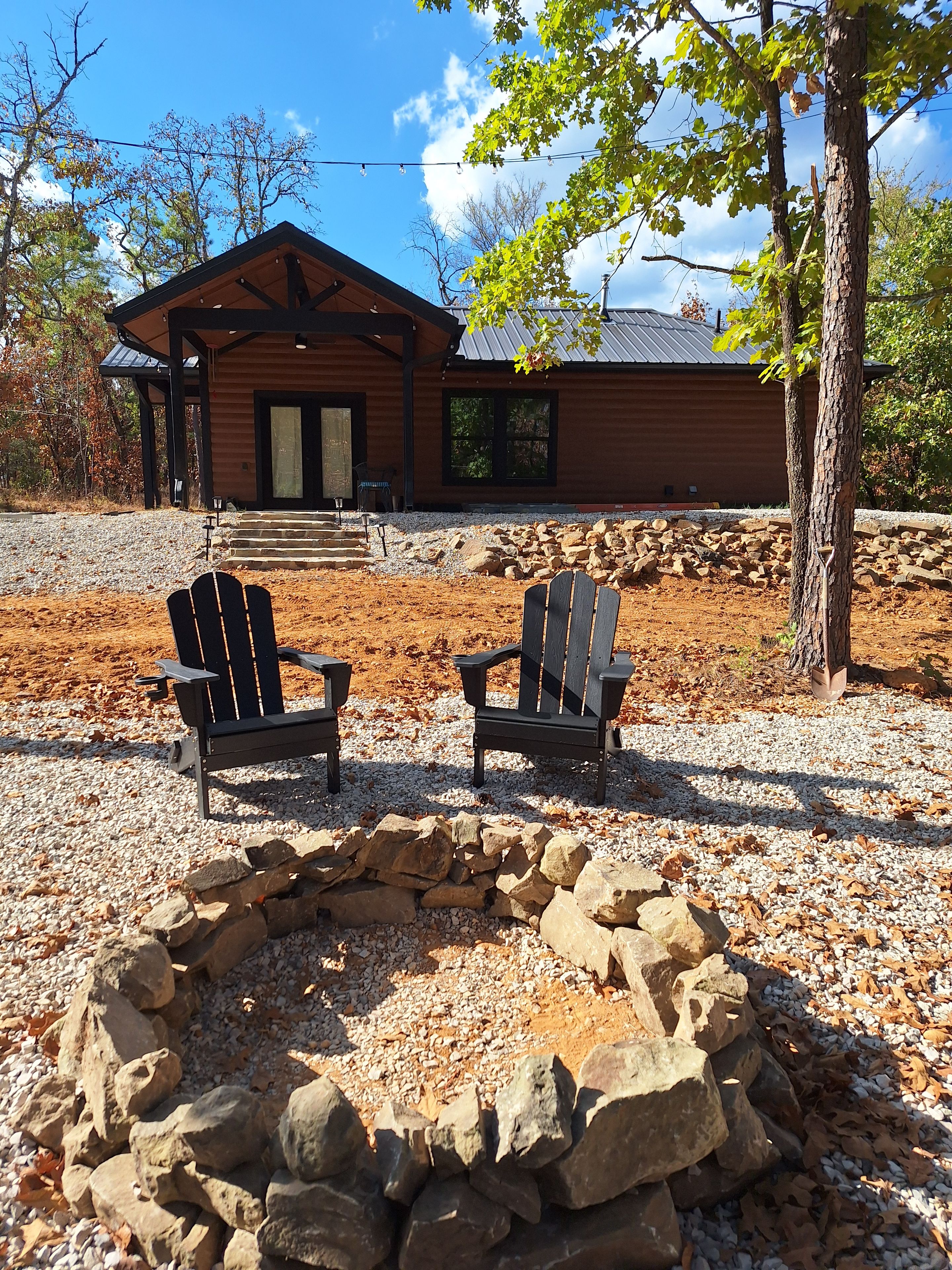 Una cabana amb una llar de pedra i dues cadires Adirondack al davant.