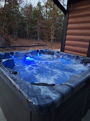 A hot tub with a wooden deck and a view of trees in the background. - Secluded Sunset a charming rustic 1-bedroom cabin in Ringold (Ringold)