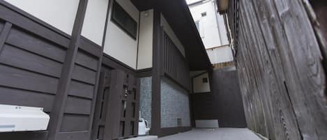 A narrow alleyway with a tiled floor, wooden walls, and a white bench.