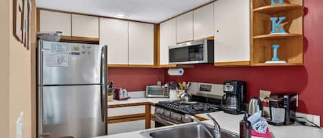 Una cocina moderna con electrodomésticos de acero inoxidable, gabinetes de madera y una pared de acento roja.