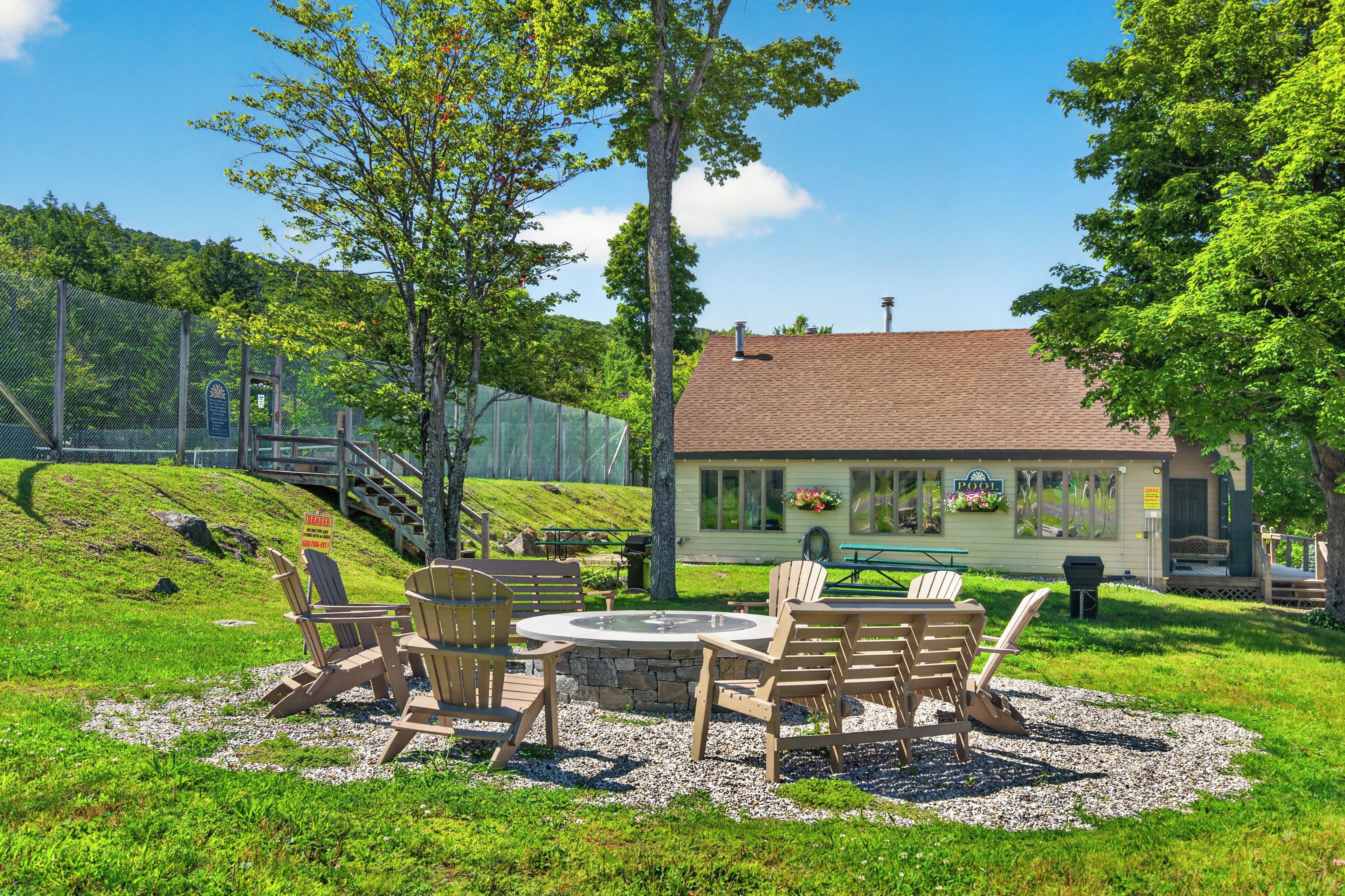 A poolside area with outdoor seating and a building with a sign indicating a pool.