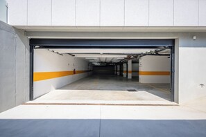 A parking garage entrance with a concrete floor, white walls, and orange stripes. - Wave 2.2 (Vila Nova de Gaia)