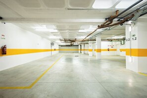 A clean, empty parking garage with white walls and yellow stripes, featuring numbered parking bays and visible fire extinguishers. - Wave 2.2 (Vila Nova de Gaia)