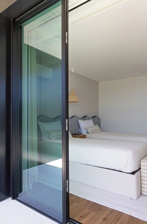A modern bedroom with a glass door leading to a balcony, a bed with white bedding, and a bedside table with a lamp. - Wave 2.2 (Vila Nova de Gaia)