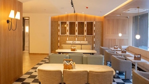 A modern interior with a checkered floor, seating areas, and a central table with chairs. - Classic With Twin Bed Checkin Amritsar (Amritsar)