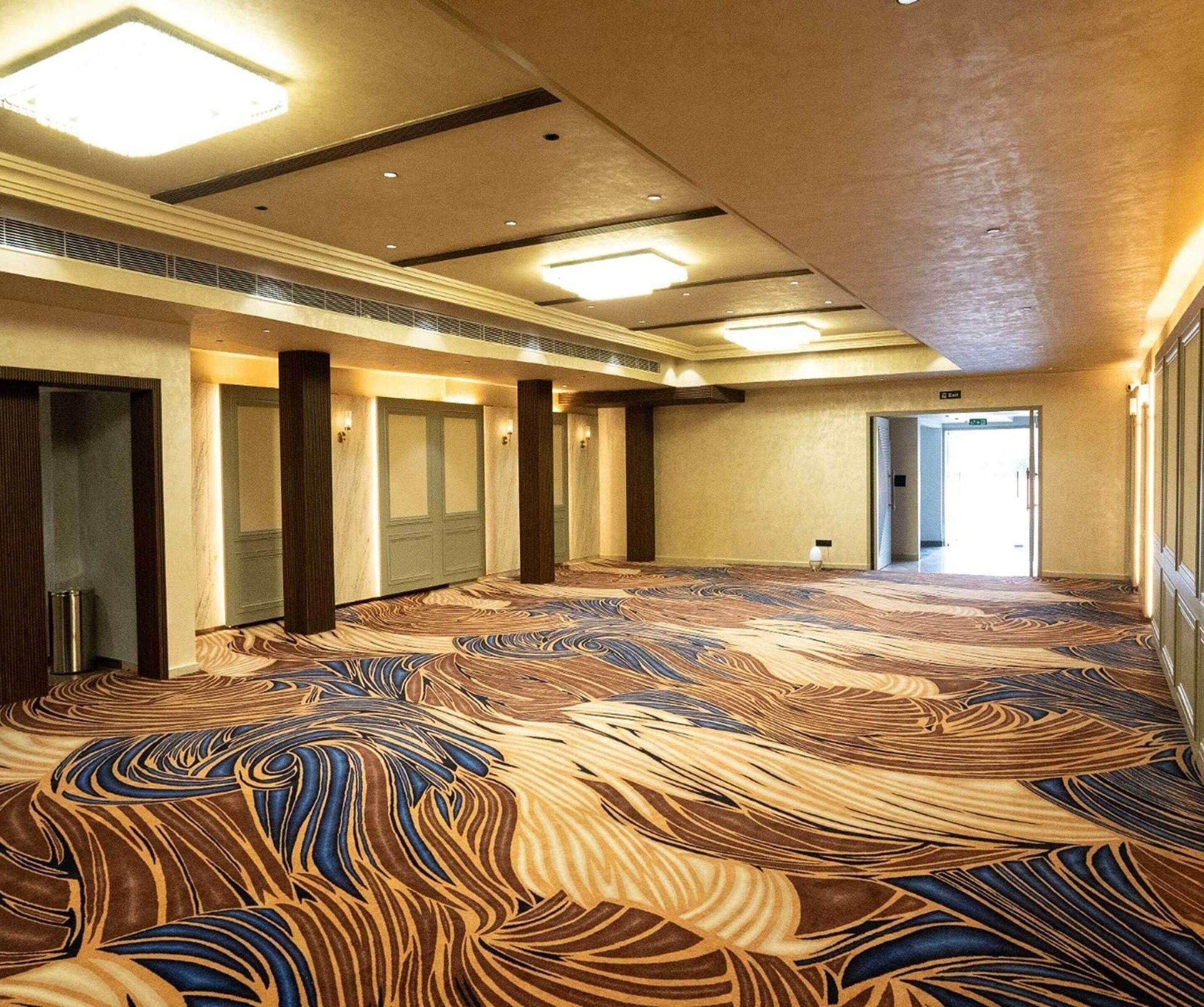 Ein Hotelgang mit gemustertem Teppich, Türen und Deckenleuchten.