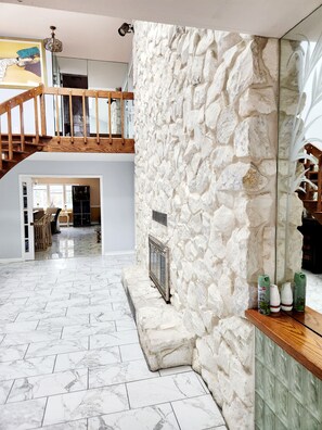 A spacious room with a stone wall, a wooden staircase, and a marble floor.