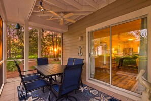 A covered patio with a table and chairs, a ceiling fan, and a view of the interior through glass doors. - First Floor Cottage at Hidden Dunes, Near Tennis Courts (Miramar Beach)