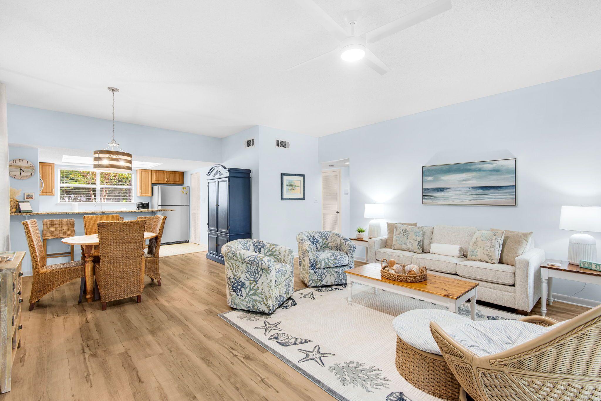 A spacious living area with a dining table, wicker chairs, a sofa, and a coffee table.