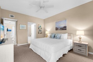 A bedroom with a large bed, a nightstand, a lamp, and artwork on the walls. - First Floor Cottage at Hidden Dunes, Near Tennis Courts (Miramar Beach)