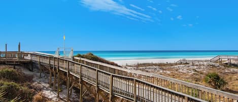 A wooden boardwalk leading to a beach with clear skies.