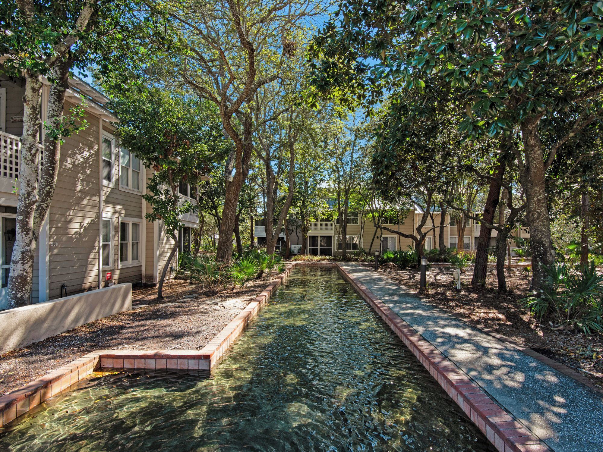 A serene courtyard with a clear water feature, surrounded by trees and buildings.