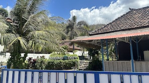 Um edifício com telhado de azulejos, cercado por palmeiras e um muro azul.