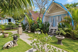 A bungalow with a tiled roof, surrounded by lush greenery and potted plants. - Belvilla Bakung Cozy Cottage  (Penida Island)