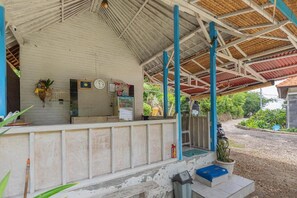 Área externa coberta com uma mesa de recepção, um relógio e um pequeno jardim.