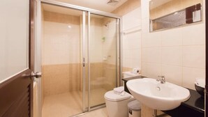 A bathroom with a glass shower enclosure, a white sink, and a toilet.