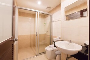 A bathroom with a glass shower enclosure, a white sink, and a toilet.