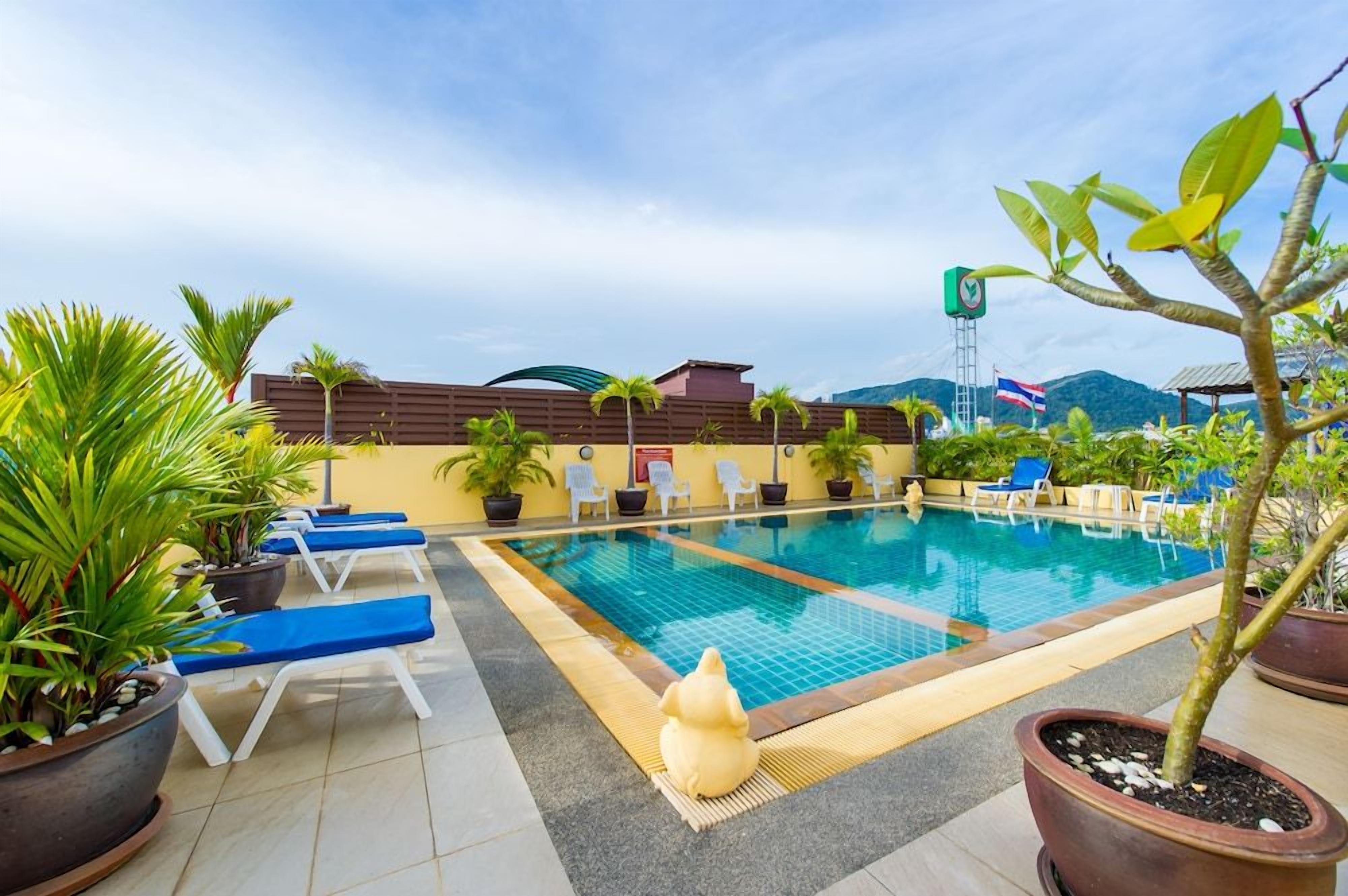 Una piscina con sillones de descanso y plantas en macetas.
