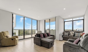 A spacious living area with large windows, a grey sofa set, and a modern design. - KozyGuru | Fairfield | Stylish Stay Near Station (Fairfield)